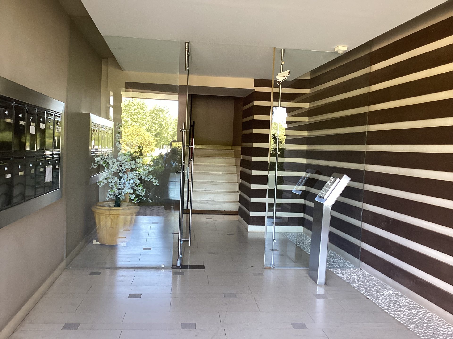 Είσοδος πολυκατοικίας με γυάλινες πόρτες, γραμματοκιβώτια και σκάλα προς τον 1ο όροφο
